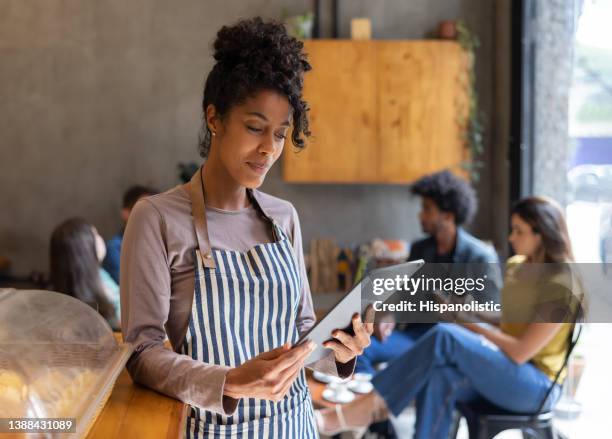 kellnerin in einem café mit einem tabletcomputer - native african ethnicity stock-fotos und bilder