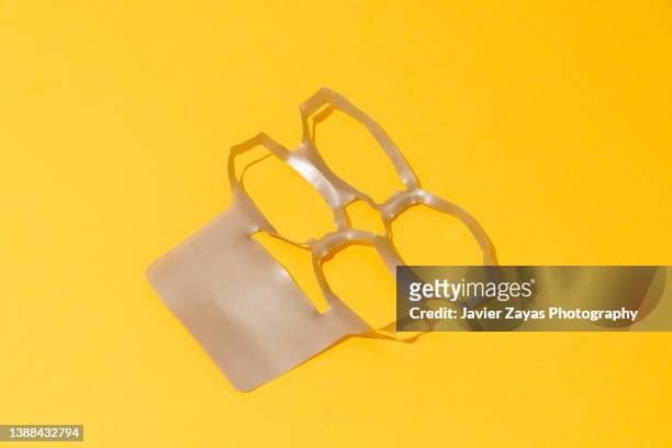 plastic rings on yellow background - six-pack yokes - disposable stock pictures, royalty-free photos & images