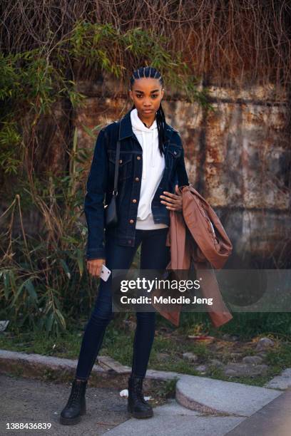 Jamaican model Shantae Leslie wears a denim jacket, white hoodie, small black purse, blue skinny jeans, and black boots after the Ports 1961 show at...