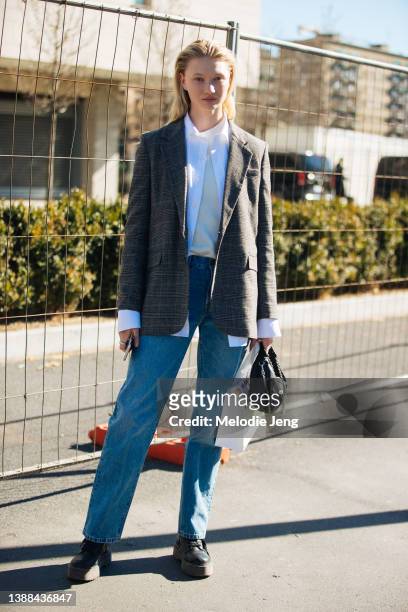 Swedish model Evelina Lauren wears a gray check blazer, white shirt, blue jeans, black boots, and small black purse after the Jil Sander show during...