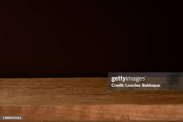 wooden table against dark wall background - rustic table stock pictures, royalty-free photos & images