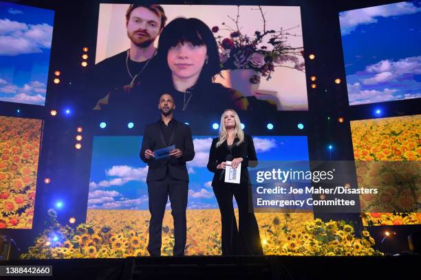 Presenters Marvin Humes and Emma Bunton speak via link to Billie Eilish and Finneas O'Connell during a Concert for Ukraine at Resorts World Arena on...