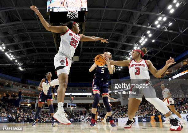 Paige Bueckers of the UConn Huskies heads for the net as Kayla Jones and Kai Crutchfield of the NC State Wolfpack defend in the first half during the...