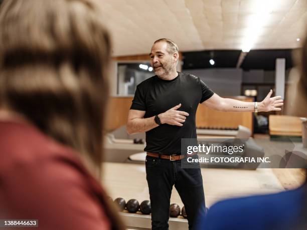 bowling alley owner interacting with new employees - bowling alley stock pictures, royalty-free photos & images