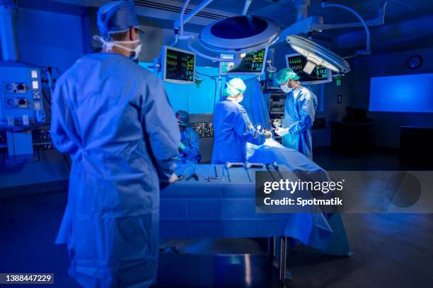 surgical team in hospital operating theatre performing laparoscopy - doctor scrubs stock pictures, royalty-free photos & images