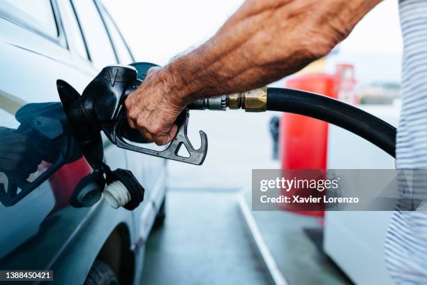 close up senior man hands refueling his vehicle at gas station - oil price increase concept - comprar coche fotografías e imágenes de stock