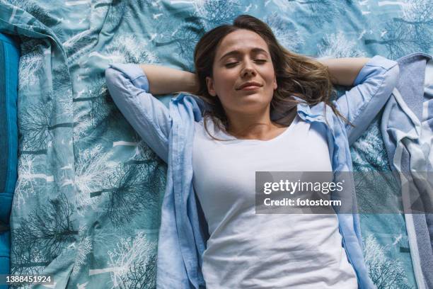 foto di una giovane donna felice sdraiata sul suo letto, le mani dietro la testa, gli occhi chiusi - supino foto e immagini stock