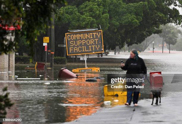 Woman walks her dog on a flooded road on March 30, 2022 in Lismore, Australia. Evacuation orders have been issued for towns across the NSW Northern...