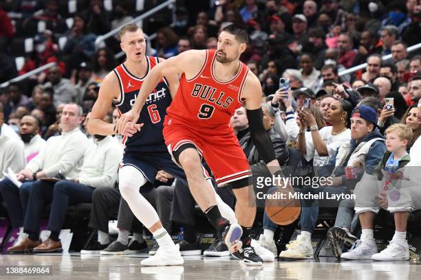 Nikola Vucevic of the Chicago Bulls dribbles by Kristaps Porzingis of the Washington Wizards in the second quarter during a NBA basketball game at...