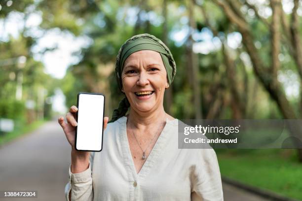 woman with cancer holding smartphone - cancer patient portrait stock pictures, royalty-free photos & images