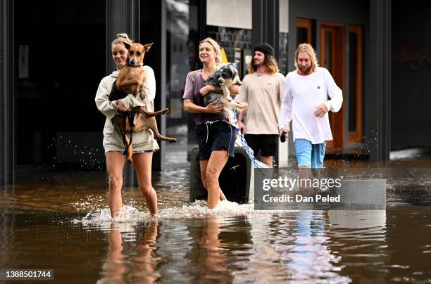 People walk through floodwater on March 30, 2022 in Byron Bay, Australia. Evacuation orders have been issued for towns across the NSW Northern Rivers...