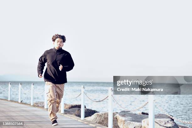 a young man running along the breakwater. - self discipline stockfoto's en -beelden