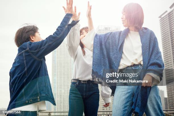 three young people share their joy with a high-five. - five friends unity stock pictures, royalty-free photos & images