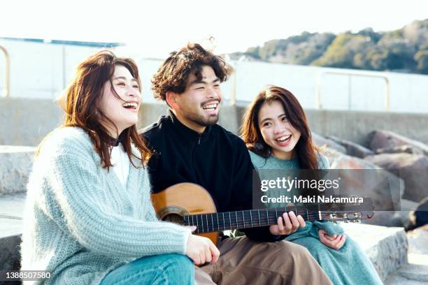 a man plays the guitar and two women sing together. - friendly match stockfoto's en -beelden