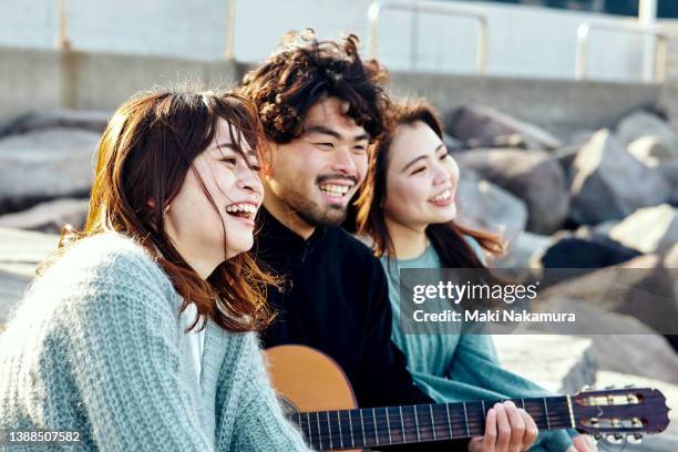 a man plays the guitar and two women sing together. - friendly match stockfoto's en -beelden