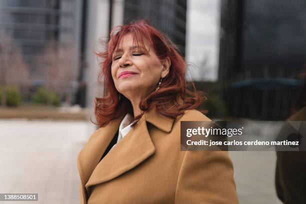 mature redhead senior mature woman with closed eyes relaxed after work, business woman, on the street - woman smiling eyes closed stock pictures, royalty-free photos & images