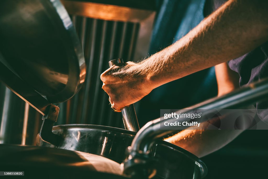 Male worker operating machinery in brewery