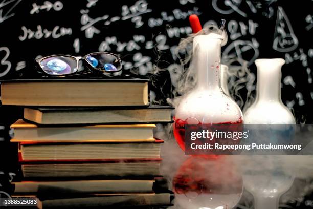 test tubes and conical flasks, science beakers for research on a classroom desk with blackboard of chemistry teaching. - conical flask stock pictures, royalty-free photos & images