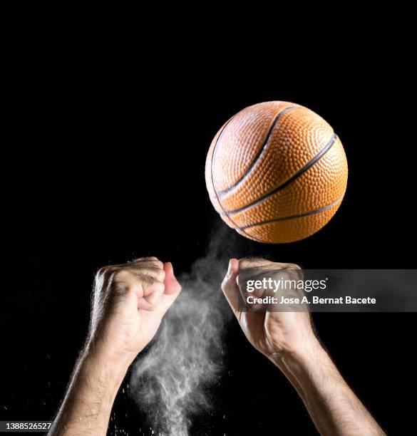 hands of a basketball player catching a ball on a black background. - ballon rebond stock-fotos und bilder