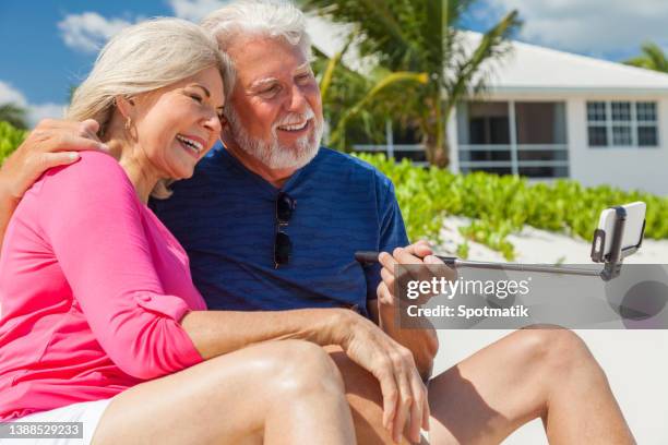 loving retired caucasian couple using selfie stick caribbean - sea iphone stock pictures, royalty-free photos & images