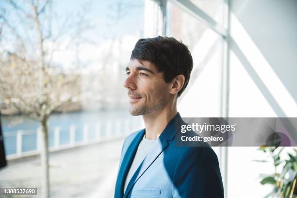 businessman looking out of window from office - man side view stock pictures, royalty-free photos & images