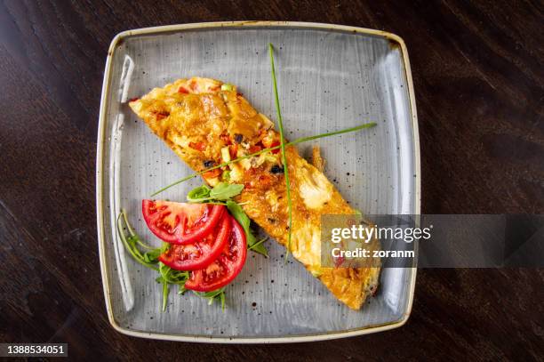 egg omelet with avocado and cherry tomato pieces served with sliced tomato and arugula - arugula stock pictures, royalty-free photos & images