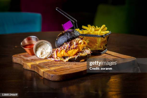 fried breaded meat in coal bun with dressed salad, served with french fries and sauces - schnitzel stock pictures, royalty-free photos & images