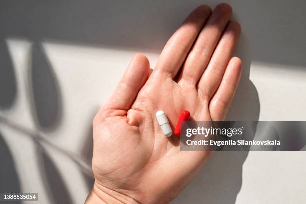 woman's hand holding red pills. close-up. - red pill stock pictures, royalty-free photos & images