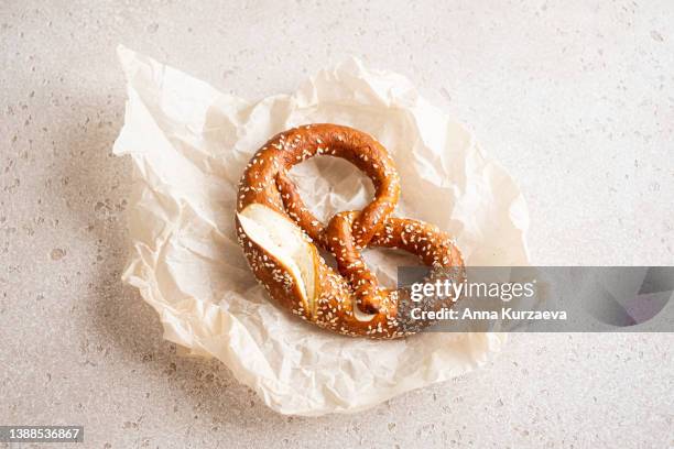 close-up of homemade pretzel bread with sesame seeds on a parchment paper on concrete background, selective focus - wachspapiere stock-fotos und bilder