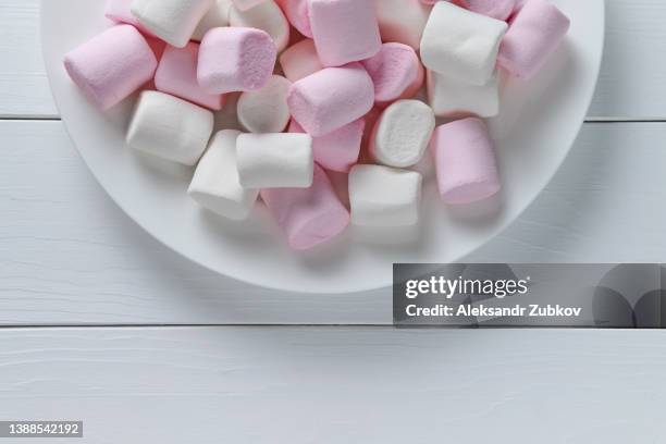 beautiful sweet airy soft white and pastel pink marshmallows lie on a plate, on a wooden table. the concept of food and unhealthy eating. food background. - excess product stock pictures, royalty-free photos & images