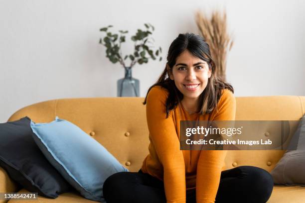 fashionable young woman with brunette hair, relaxing on the sofa with crossed legs. - vie simple photos et images de collection