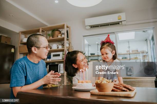 ragazza che si sente felice con la sua torta di compleanno. - parents children blow candles asians foto e immagini stock