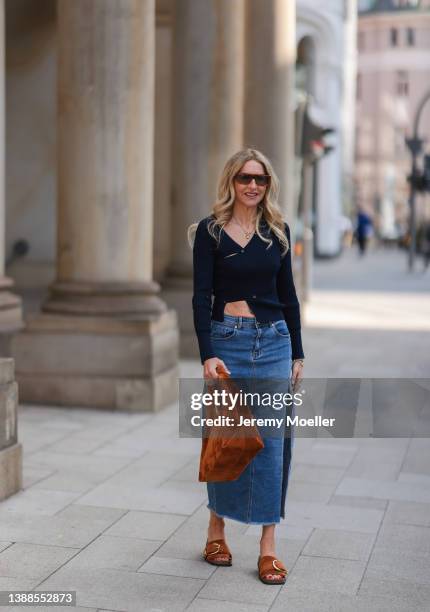 Sue Giers is seen wearing Jacquemus navy blue cut out crop top, Stella Sabatoni blue denim skirt, Khaite brown leather sandals and matchy brown...