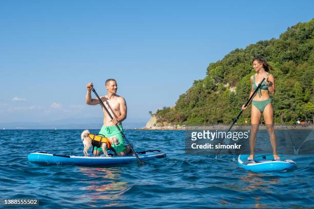 couple paddleboarding in sea - slovenia beach stock pictures, royalty-free photos & images