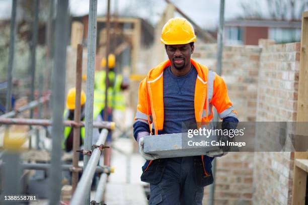 male construction worker carrying brick at construction site - dedication brick stock pictures, royalty-free photos & images