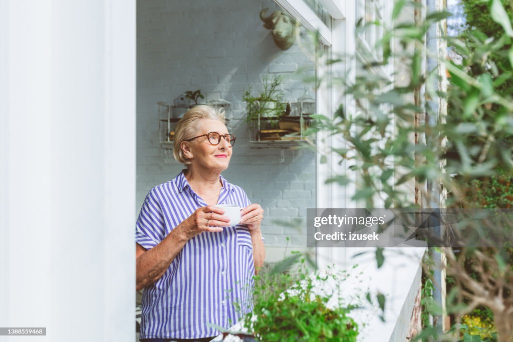 Elderly woman having coffee at window