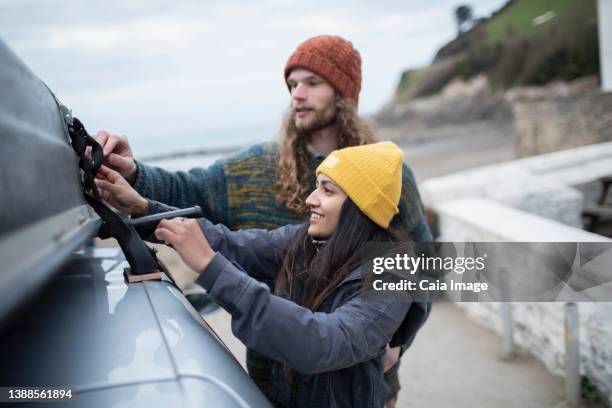 couple fastening rooftop cargo on car - knitted car stock pictures, royalty-free photos & images