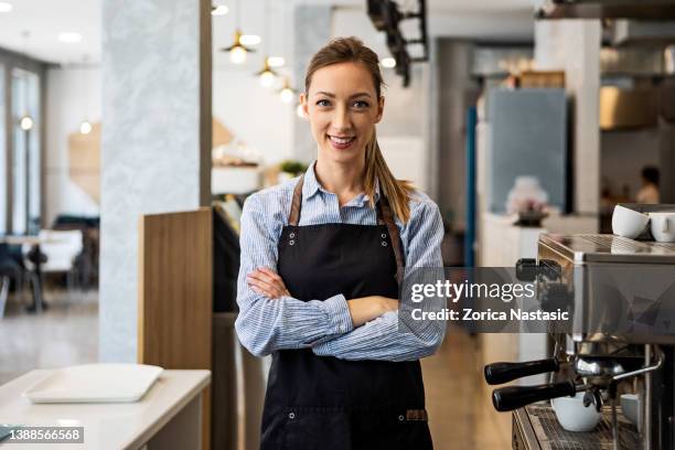 smiling coffee shop owner standing on her workplace with arms crossed - barista coffee restaurant stock pictures, royalty-free photos & images