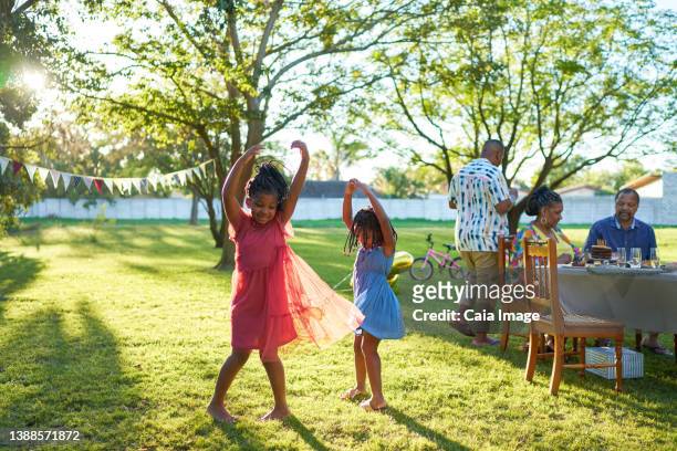 happy carefree sisters dancing in sunny summer park - sunny backyard stock pictures, royalty-free photos & images
