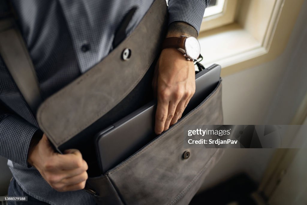 Nahaufnahme eines unkenntlichen Geschäftsmannes, der seinen Laptop aus der Aktentasche holt