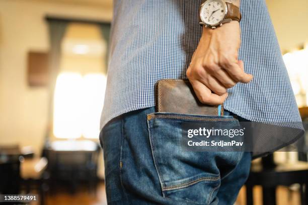 un homme méconnaissable met son portefeuille en cuir dans la poche arrière du jean - leather pants photos et images de collection