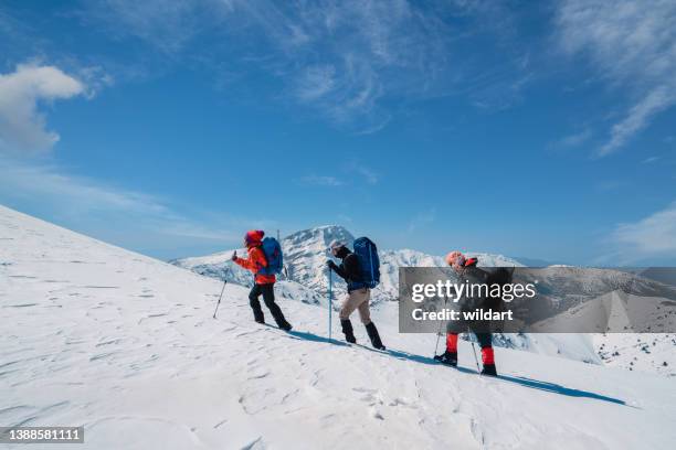 successful mountain climber team is climbing in a row on the ridge of the  high altitude snowy mountain summit in winter - ice pick stockfoto's en -beelden