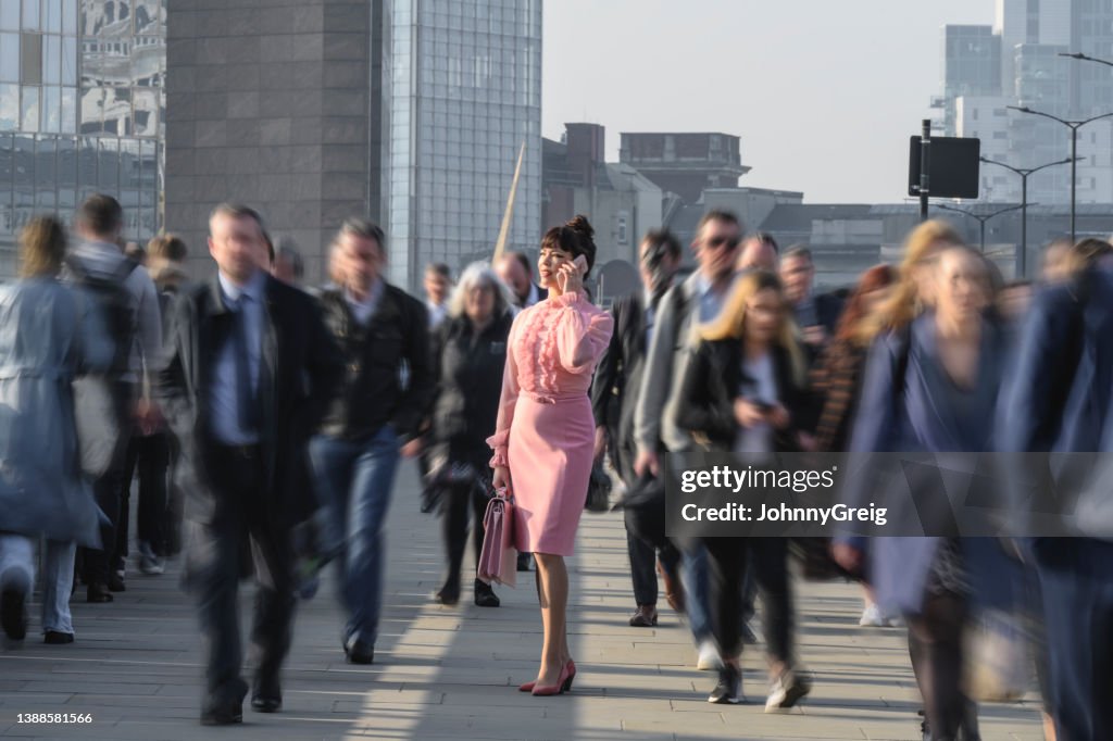 Führungskraft in Rosa gekleidet mit Telefon während des morgendlichen Pendelns