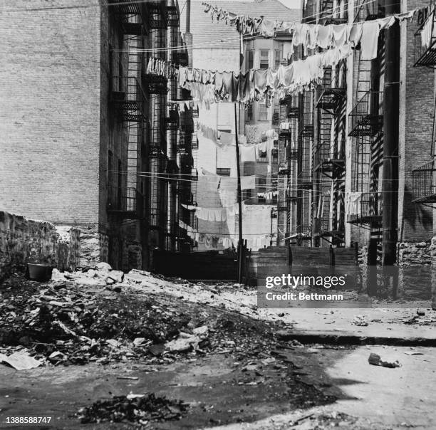 Clotheslines stung between two tenement building with the ground below covered in waste where occupants have thrown their garbage into the courtyard...