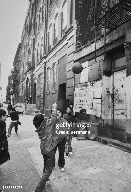 Children playing basketball, the two bottom rungs of the fire escape ladder are a good substitute for a basket hoop, on the Lower East Side of...