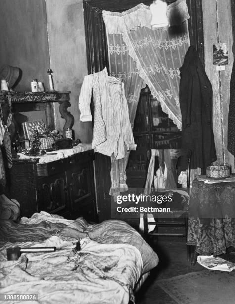 The crowded corner of a typical slum property with clothes strewn around and a folding bed in New York City, New York, 27th October 1937.