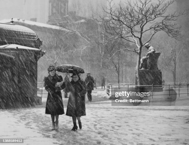 Pedestrians use an umbrella to shelter themselves from the snow and freezing rain in Herald Square, New York City, New York, 22nd March 1940. In the...