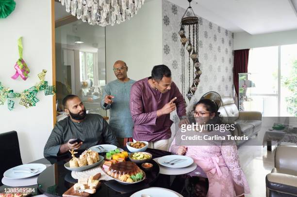 family gathering around the dinner table for hari raya meal - lunch argument stock-fotos und bilder