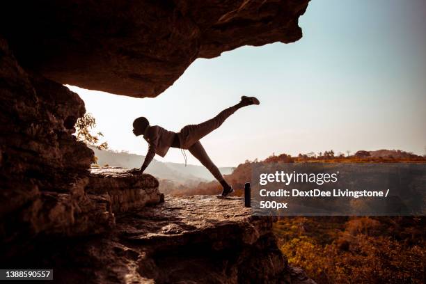woman practicing yoga on rock against clear sky during sunset,asiafo amanfro,ghana - ghana woman stock pictures, royalty-free photos & images