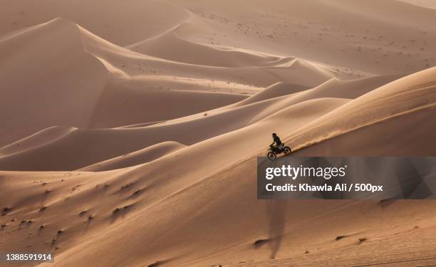 man riding motorcycle on sand dune in desert - moto desierto fotografías e imágenes de stock